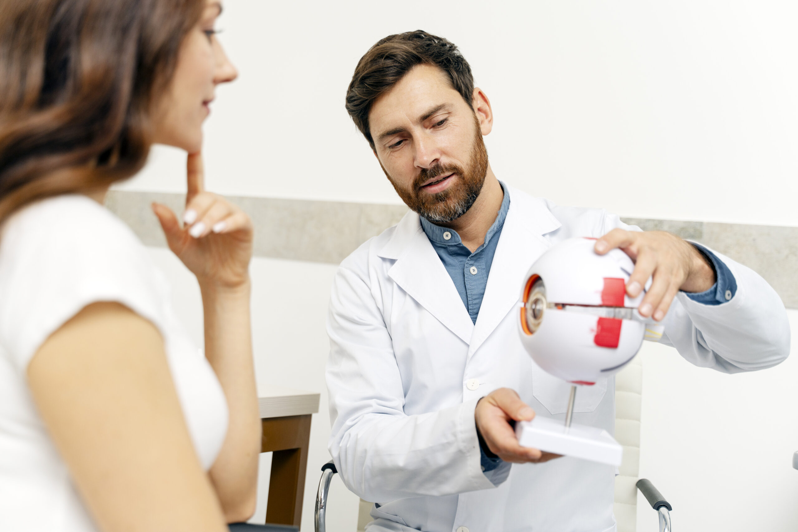 Doctor talking with female patient while holding eyeball model. Health care, science concept